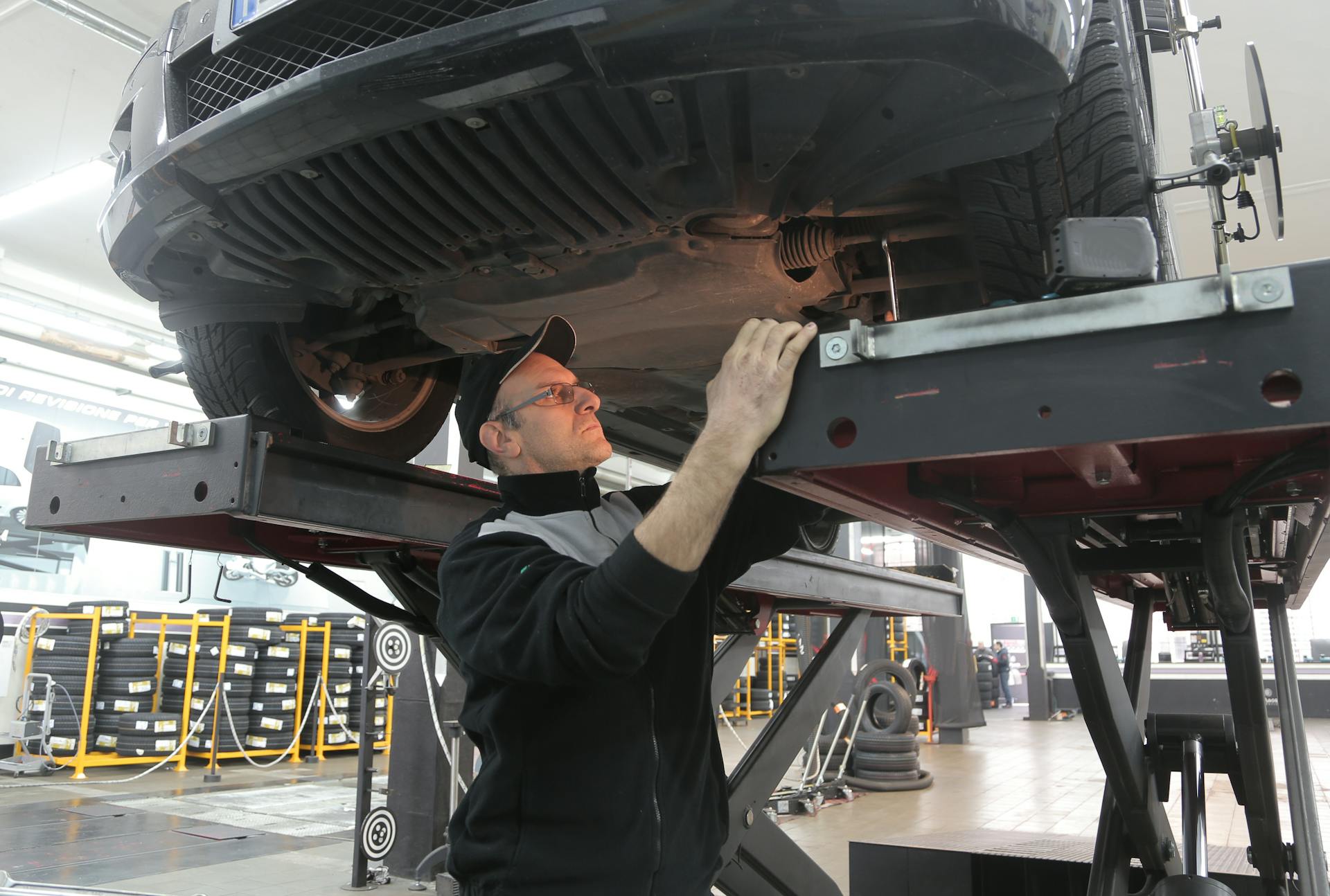 Mechanic inspecting vehicle undercarriage and transmission components